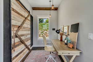 Office space with a barn door, dark wood-type flooring, and baseboards