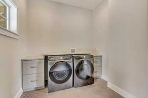 Washroom featuring separate washer and dryer, cabinet space, and baseboards