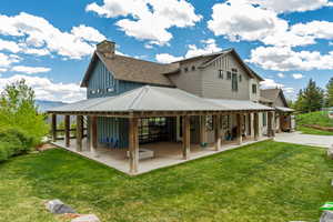 Rear view of house with board and batten siding, a patio, and a yard