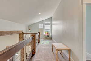 Loft space featuring vaulted ceiling, an upstairs landing, carpet floors, baseboards, and recessed lighting