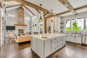 Kitchen featuring a sink, stainless steel appliances, beam ceiling, white cabinetry, and light countertops