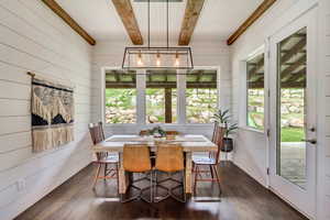 Dining room with dark wood-style flooring, wooden walls, and wood ceiling with exposed beams