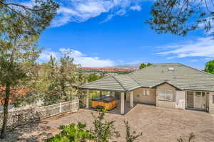 Back of house featuring a hot tub, a tile roof, stucco siding, a patio area, and a fenced backyard