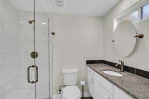 Full bathroom with toilet, vanity, and a stall shower