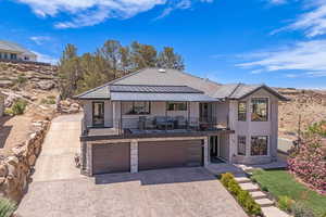 View of front facade featuring an attached garage, decorative driveway, a balcony, and stone siding