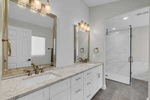 Full bathroom with a marble finish shower and double vanity