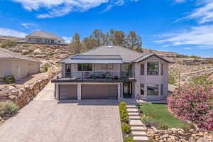 View of front of home featuring a standing seam roof, decorative driveway, a balcony, an attached garage, and metal roof