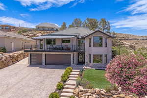 Contemporary home with a balcony, an attached garage, decorative driveway, and stone siding