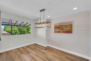Unfurnished room with baseboards, wood finished floors, wooden walls, and recessed lighting
