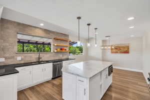Kitchen featuring dishwasher, a sink, dark stone countertops, backsplash, and recessed lighting