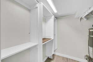Walk in closet featuring wood finished floors and water heater