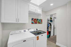 Washroom with cabinet space, washer and clothes dryer, and baseboards