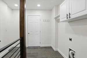 Laundry room with cabinet space, hookup for an electric dryer, dark tile patterned flooring, baseboards, and recessed lighting