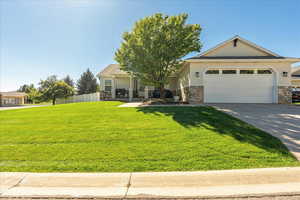 View of front facade featuring stone siding, driveway, stucco siding, and a garage