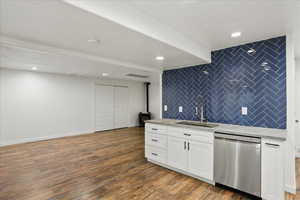 Kitchen featuring white cabinetry, stainless steel dishwasher, dark wood-style flooring, light stone counters, and recessed lighting