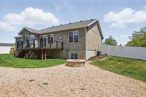 Rear view of property featuring cooling unit, a wooden deck, stucco siding, and a fire pit
