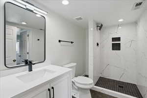 Full bath featuring toilet, vanity, a marble finish shower, recessed lighting, and tile patterned floors