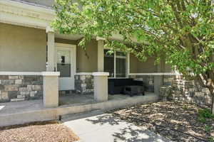 Property entrance featuring stone siding, a porch, and stucco siding