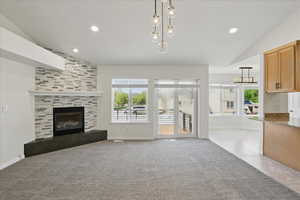 Unfurnished living room with lofted ceiling, a fireplace, carpet, baseboards, and recessed lighting