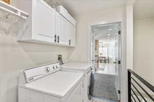 Laundry room with cabinet space, separate washer and dryer, and light carpet