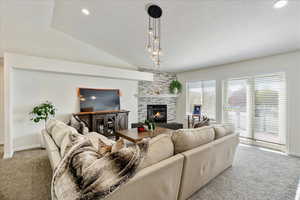 Living area featuring light carpet, a large fireplace, lofted ceiling, recessed lighting, and a textured ceiling
