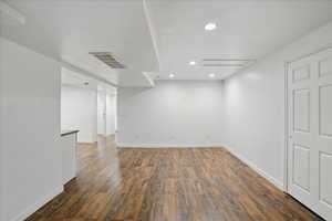 Below grade area with dark wood-type flooring, baseboards, recessed lighting, and a textured ceiling