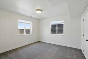 Unfurnished bedroom featuring dark carpet and baseboards