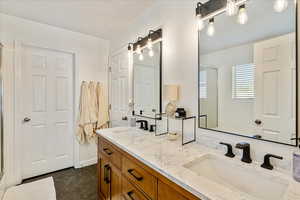 Bathroom with a stall shower, double vanity, and dark tile patterned floors