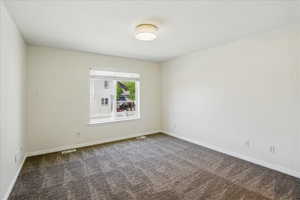 Spare room featuring dark carpet and baseboards