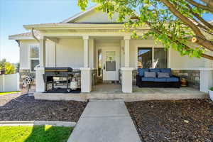 Entrance to property featuring stone siding, covered porch, stucco siding, and an outdoor hangout area