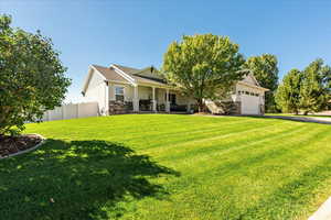 Craftsman inspired home with stone siding, stucco siding, a garage, covered porch, and asphalt driveway