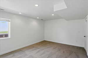 Empty room with light carpet, a textured ceiling, and recessed lighting