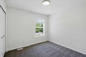 Unfurnished bedroom featuring dark colored carpet, a closet, and baseboards