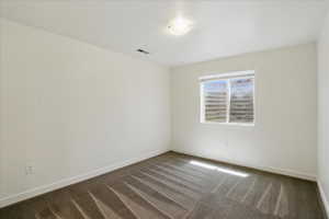 Empty room featuring dark carpet and baseboards