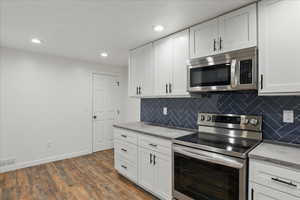 Kitchen featuring stainless steel appliances, white cabinets, light countertops, dark wood-style floors, and recessed lighting
