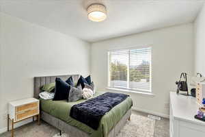 Bedroom with light colored carpet and a textured ceiling