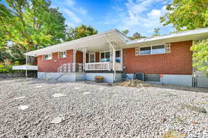 Ranch-style home featuring a porch, brick siding, and central AC unit