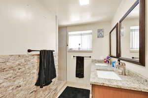 Bathroom with double vanity, a tile shower, and tile patterned floors
