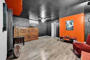Living area with ceiling fan, wood finished floors, and baseboards