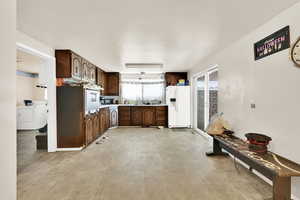Kitchen with white appliances, washer / dryer, dark brown cabinets, and light countertops