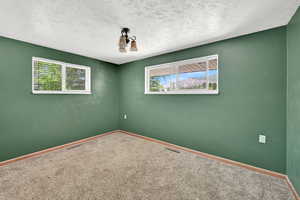 Carpeted empty room featuring baseboards and a textured ceiling