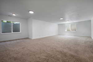 Extra large bedroom with light colored carpet, baseboards, plenty of natural light, and a textured ceiling