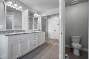 Master bath with double vanity, tile patterned floors, baseboards, and toilet