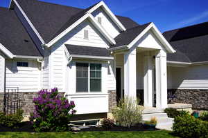 View of front of home featuring stone siding and roof with shingles