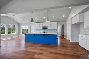 Kitchen with stainless steel microwave, light countertops, white cabinetry, baseboards, and recessed lighting