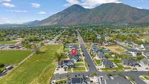 Aerial view of property and surrounding area featuring nearby suburban area and a mountain backdrop