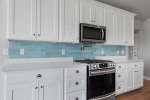 Kitchen with appliances with stainless steel finishes, light countertops, white cabinetry, and tasteful backsplash