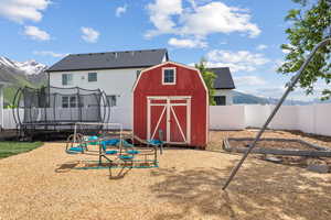 View of shed with a trampoline, a fenced backyard, and a mountain view