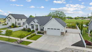 Modern inspired farmhouse featuring board and batten siding, a garage, driveway, stone siding, and a residential view