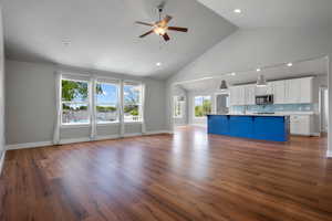 Unfurnished living room with a ceiling fan, high vaulted ceiling, a sink, dark wood-style floors, and recessed lighting